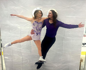 Two gala guests with their heads through a cutout of a figure skating duo