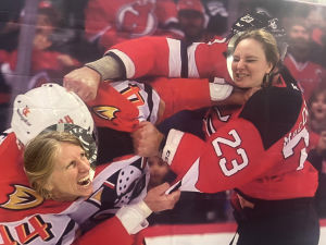 Two gala guests with their heads through a cutout of hockey players mid-scrap